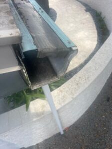 gutter cleaning service highlighting debris accumulation in the gutter system with visible dirt and leaves present
