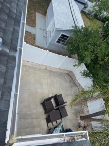 concrete patio with outdoor furniture surrounded by a white fence and greenery in a residential backyard setting