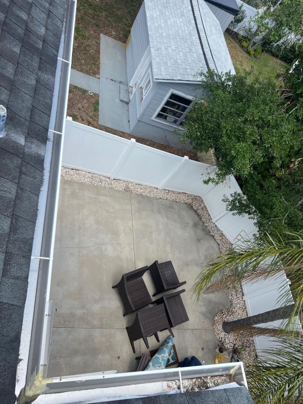 concrete patio with outdoor furniture surrounded by a white fence and greenery in a residential backyard setting