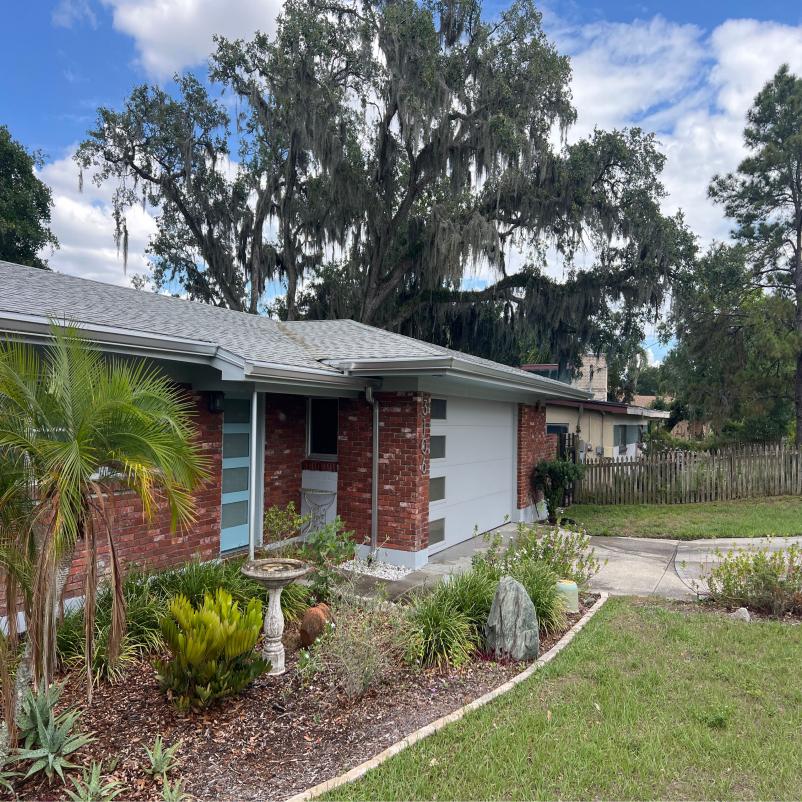 landscaping services with well-kept garden featuring palm trees and stone decorations in front of a residential brick house