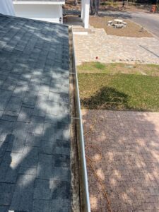 gutter cleaning service showing debris buildup along the edge of a roof with clean shingles in the background