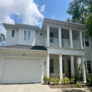 house cleaning showcasing white vinyl siding with a clear blue sky and well-maintained landscaping around the entrance