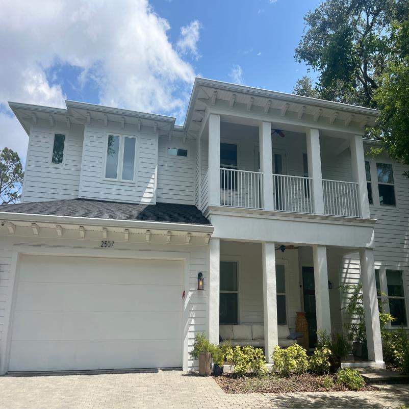 house cleaning showcasing white vinyl siding with a clear blue sky and well-maintained landscaping around the entrance
