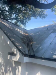 roof cleaning in progress on a metal roof showing debris along the seams and near the edges
