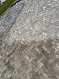 paver cleaning service showing part of driveway cleaned and part remaining dirty with a clear line of separation