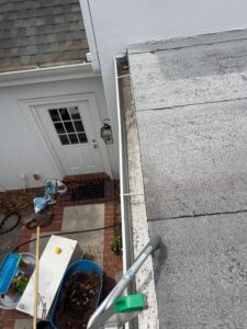gutter cleaning service being performed on a flat rooftop with equipment and a ladder visible in the scene
