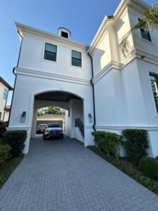 a white house with a driveway and two parked cars and well-maintained landscaping in front
