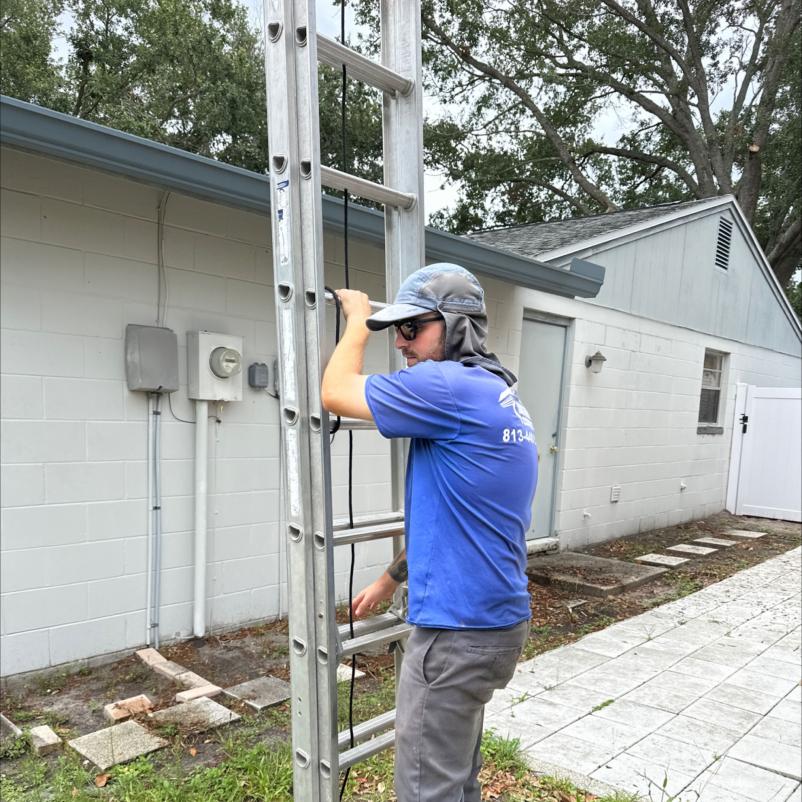 a worker from south tampa gutter and window cleaning preparing a ladder for access to a building for maintenance tasks