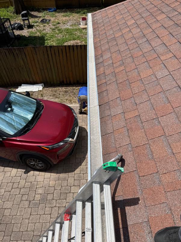 gutter cleaning service being performed on a residential roof with a ladder and a person working on the gutters