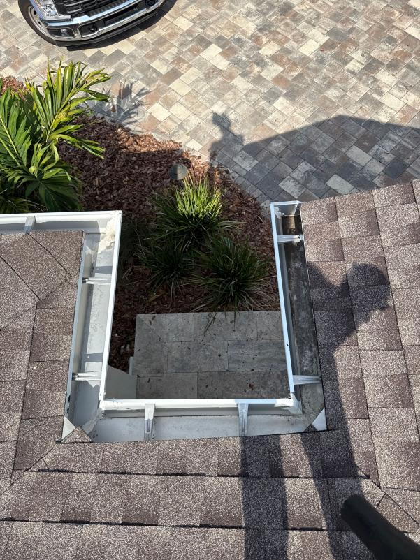 gutter cleaning service from a roof overlooking a patio area and landscaping with pavers and greenery present