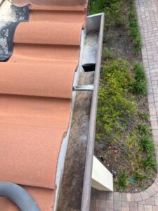 gutter cleaning showing debris buildup near a roof edge with a focus on gutter maintenance and upkeep