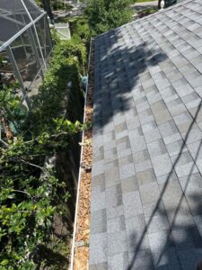 gutter cleaning service removing debris including leaves and mulch from a residential roof gutter system