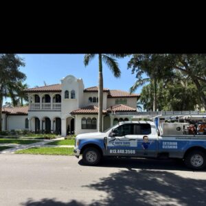 a white truck from south tampa gutter and window cleaning parked in front of a large house with palm trees