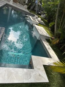 clean and clear swimming pool with clean surrounding surfaces and some fallen leaves visible in the water