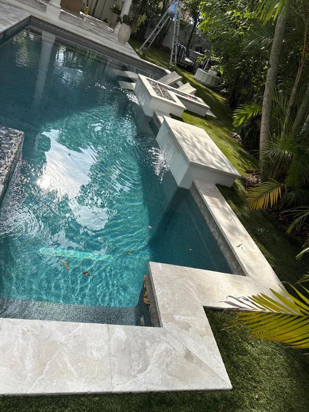 clean and clear swimming pool with clean surrounding surfaces and some fallen leaves visible in the water
