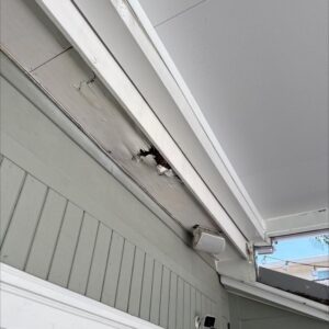 damaged soffit showing signs of wear and potential water damage near the roofline and siding area