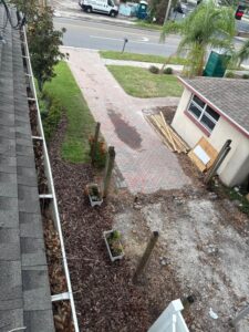 gutter cleaning service with visible debris and leaves along the roof edge and clean outdoor spaces and pavers
