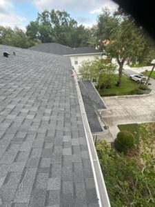 gutter cleaning service being performed on a house with a shingle roof and greenery around the property