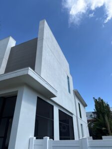 modern house exterior with large windows and a clear blue sky providing bright natural light illuminating the surface finishes