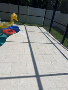 pool area with patio stones and pool floats under screen enclosure likely prepared for cleaning or maintenance activities