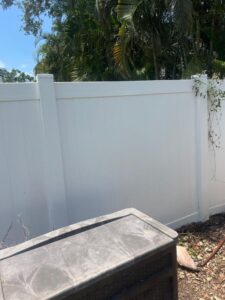 fence cleaning service with a focus on the white vinyl fence and surrounding landscaping details