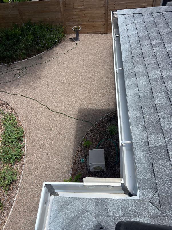 gutter cleaning service showing a clear view of the roof gutter and surrounding landscaping with a garden hose
