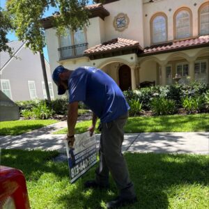 worker placing a yard sign for south tampa gutter and window cleaning in front of a house with landscaped garden