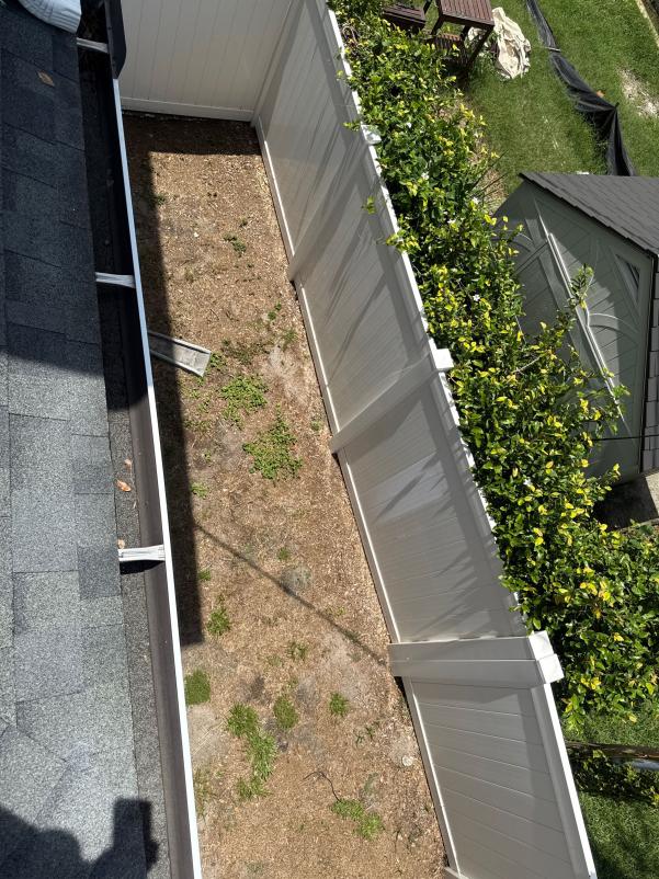 guttering installation or cleaning with a view of a fenced area and nearby structures