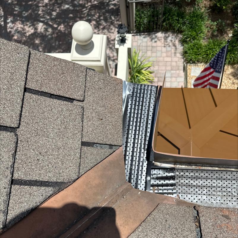 gutter installation near roof edge showing metal flashing and drainage holes with exposure to surrounding landscape and porch