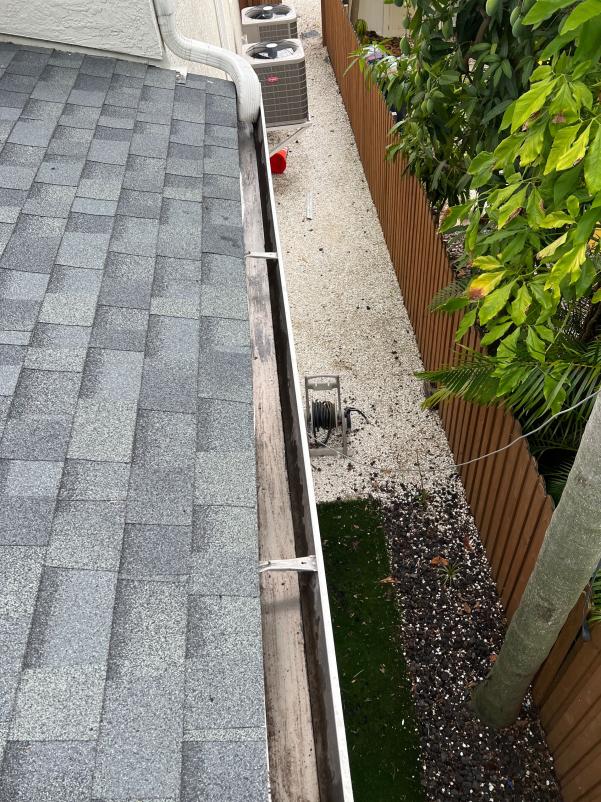 gutter cleaning service showing debris in the gutter with tools positioned nearby for efficient removal