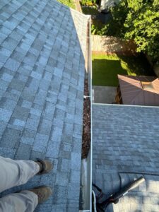 gutter cleaning with visible debris on the roof edge and equipment positioned for removal of leaves and dirt