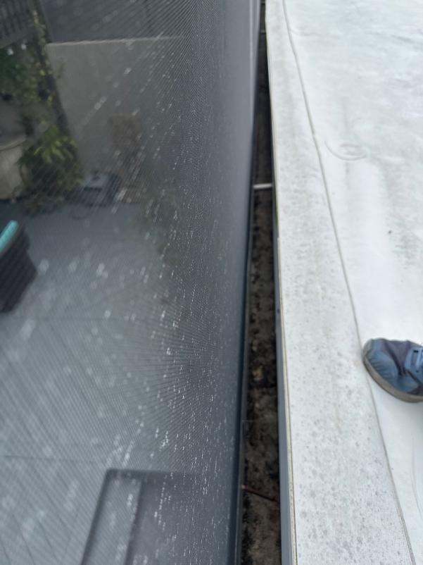 cleaning gutter and window area with debris visible on the edge and a person wearing a shoe in the corner