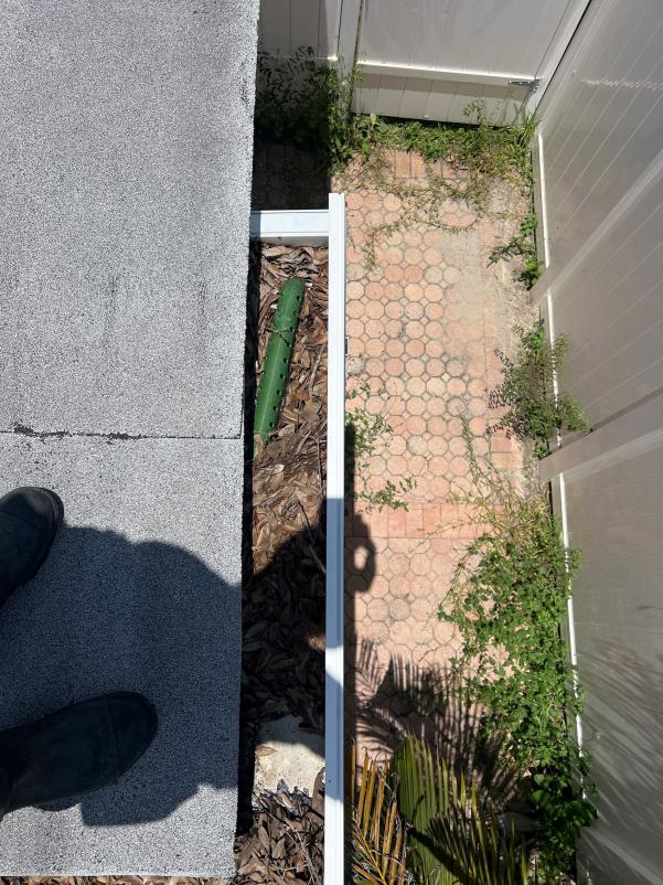 roof inspection showing foot on roofing material with greenery below and a clear path to the side