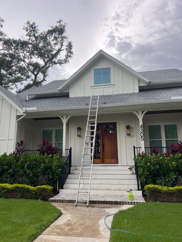 ladder positioned against a house for accessing upper windows or gutters surrounded by landscaping and concrete steps