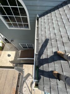 standing on roof next to gutter with tools and equipment visible preparing for cleaning services