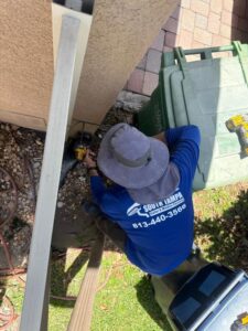 a technician from south tampa gutter and window cleaning performing maintenance on a gutter system with a power tool
