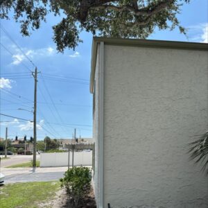 house washing a textured exterior wall with clear skies and power lines in the background