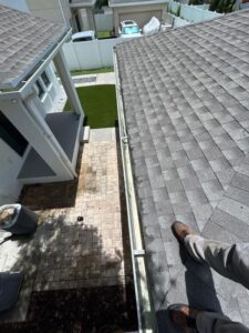 gutter cleaning services in progress on a sloped roof with a foot on the edge wearing safety shoes