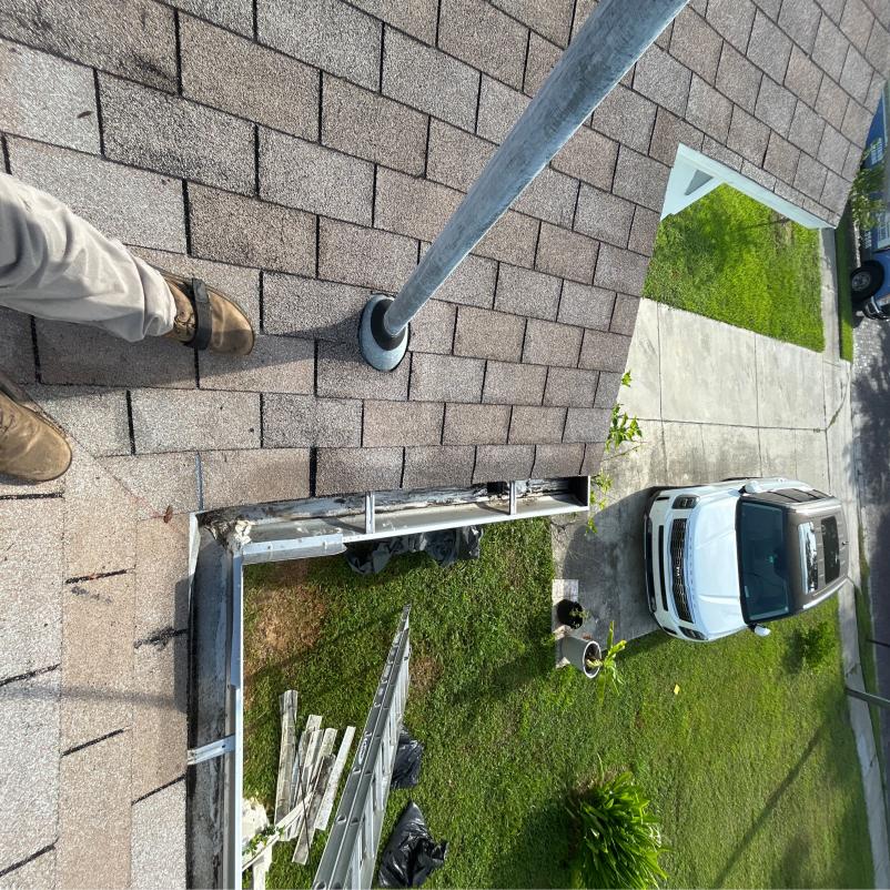 gutter cleaning in progress with ladder and equipment visible rooftops and grass in view