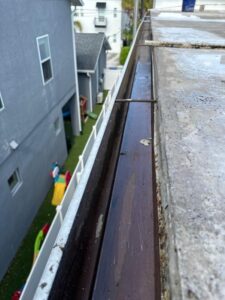 gutter inspection showing dirty gutters with debris and standing water along the edge of a roof