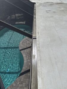 cleaning a pool enclosure with bright water and paver stones visible around the pool area