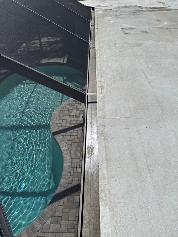 cleaning a pool enclosure with bright water and paver stones visible around the pool area