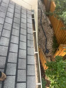 gutter cleaning service showing debris removal from a gutter and a clear view of the surrounding area and ladder