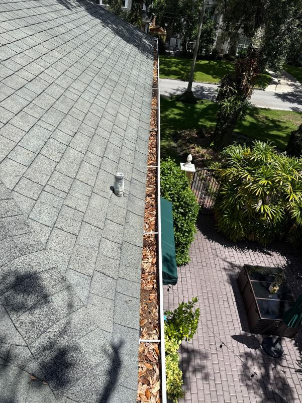 gutter cleaning service removing debris and leaves from the roof edge near the gutter system