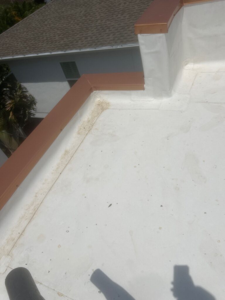 roof cleaning and maintenance showing a white surface with some dirt and debris near the edges and corners