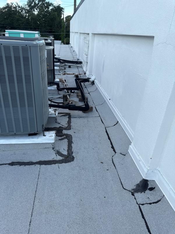cracked rooftop surface with plumbing and hvac units visible indicating potential maintenance or inspection work needed