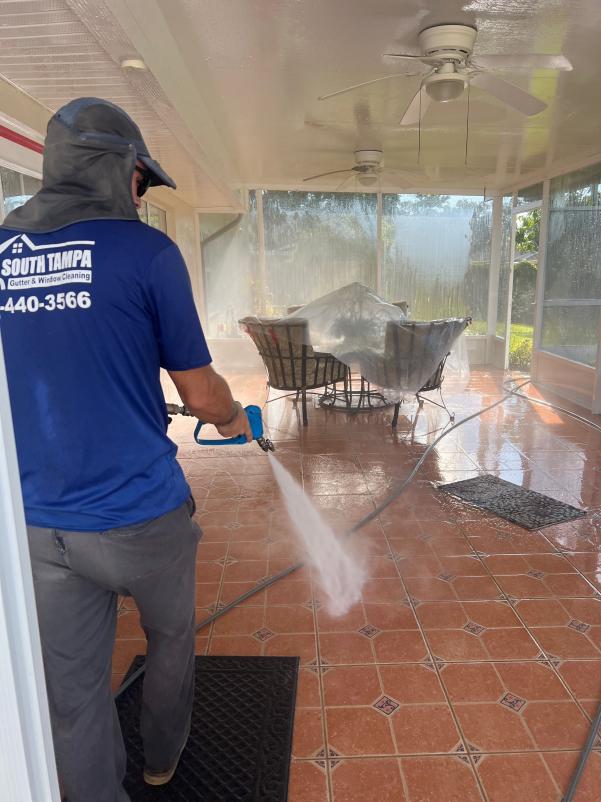 south tampa gutter and window cleaning pressure washing a patio area with tile flooring and outdoor furniture covered in plastic