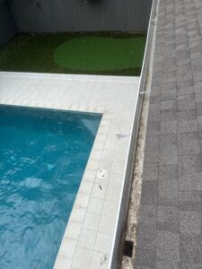 cleaning debris from pool edge and inspecting roof near swimming pool area